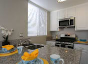 Thumbnail 16 of 34 - A kitchen with granite countertops and a stainless steel sink.