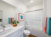 Thumbnail 30 of 33 - A white bathroom with a toilet, sink, and shower.
