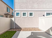 Thumbnail 31 of 33 - A beige house with a white fence and a small garden.