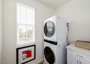Thumbnail 24 of 33 - A white front loading washing machine in a laundry room.