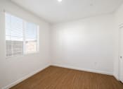 Thumbnail 25 of 33 - A room with a wooden floor and a window with blinds.