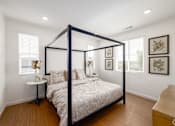 Thumbnail 13 of 33 - A bedroom with a four poster bed and a nightstand with a lamp.