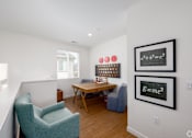 Thumbnail 16 of 33 - A room with a chair, table, and two framed equations on the wall.
