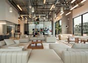 Thumbnail 18 of 29 - A modern living room with white furniture and a glass wall.