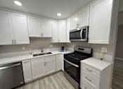 Thumbnail 2 of 12 - A kitchen with white cabinets and stainless steel appliances.
