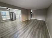 Thumbnail 3 of 12 - A room with a wood floor and a refrigerator.