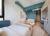 Thumbnail 4 of 29 - A bedroom with a bed, a chair, and a painting on the wall.