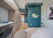 Thumbnail 5 of 29 - A modern bedroom with a bed, chair, and a painting on the wall.
