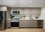 Thumbnail 3 of 29 - A modern kitchen with a stainless steel refrigerator, a microwave above the stove, and a sink with a faucet.