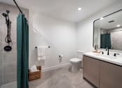 Thumbnail 28 of 29 - A bathroom with a white toilet, a sink, and a shower.