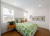 Thumbnail 5 of 33 - A bedroom with a bed, a table, and pictures on the wall.