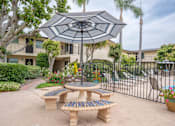Thumbnail 11 of 13 - A patio with a table and chairs under an umbrella.
