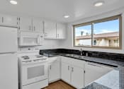 Thumbnail 2 of 13 - A kitchen with white appliances and cabinets.