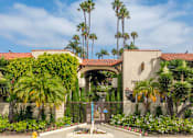 Thumbnail 21 of 25 - A building with a gate and palm trees in front.