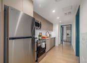 Thumbnail 21 of 29 - A modern kitchen with a stainless steel refrigerator and wooden flooring.