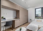 Thumbnail 8 of 29 - A bedroom with a bed, desk, and chair.
