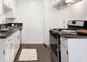 Thumbnail 4 of 23 - Modern kitchen with black countertops, white cabinets, and gas stove