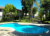 Thumbnail 12 of 23 - Resort-style pool surrounded by lush landscaping and lounge chairs