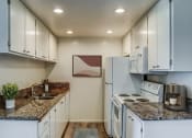 Thumbnail 6 of 14 - a kitchen with white appliances and granite counter tops