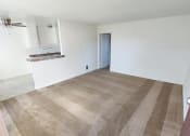 Thumbnail 22 of 24 - an empty living room with a kitchen in the background