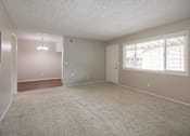 Thumbnail 5 of 32 - A spacious room with a carpeted floor and a window with blinds.