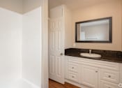 Thumbnail 32 of 32 - A bathroom with a white door and a black countertop.
