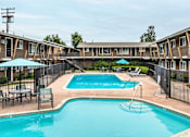 Thumbnail 1 of 32 - A swimming pool surrounded by a black fence and chairs.