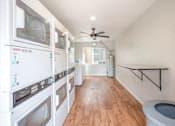Thumbnail 11 of 32 - A laundry room with a washer and dryer on the left and a toilet on the right.