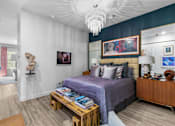 Thumbnail 1 of 38 - A bedroom with a purple bed and a wooden nightstand at The Quarter Lofts Apartments, Jackson, MS, 39216