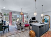 Thumbnail 3 of 38 - A modern kitchen with a grey island and a living room with a sofa and a TV. at The Quarter Lofts Apartments, Jackson, 39216