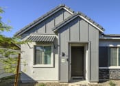 Thumbnail 2 of 31 - a gray house with a black door and a blue sky at Village of Chandler Apartments, Arizona, 85249