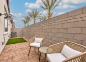 Thumbnail 6 of 31 - a patio with two chairs and a table next to a wall at Village of Chandler Apartments, Chandler, 85249