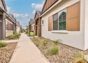 Thumbnail 5 of 31 - a row of houses with a sidewalk in front of them at Village of Chandler Apartments, Chandler, AZ
