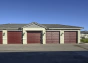 Thumbnail 14 of 31 - a garage with red doors in front of a house at Village of Chandler Apartments, Chandler