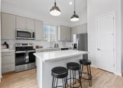 Thumbnail 22 of 31 - a kitchen with a large island with three stools at Village of Chandler Apartments, Chandler, AZ, 85249