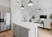Thumbnail 26 of 31 - a white kitchen with a large island and a stainless steel refrigerator at Village of Chandler Apartments, Chandler