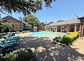 Thumbnail 2 of 50 - A pool surrounded by a patio with chairs and a hedge.