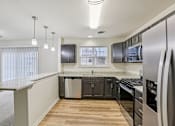 Thumbnail 6 of 48 - A modern kitchen with stainless steel appliances and wooden floors.