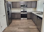 Thumbnail 11 of 48 - A kitchen with a refrigerator, oven, and microwave.