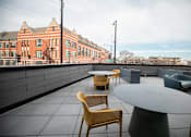 Thumbnail 12 of 19 - A patio with a table and chairs overlooking a brick building.