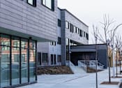 Thumbnail 9 of 19 - A modern building with a grey exterior and a glass entrance.