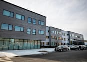 Thumbnail 13 of 19 - A modern building with a parking lot in front.