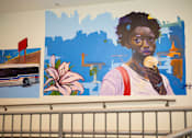 Thumbnail 3 of 19 - A woman is eating an ice cream cone in front of a painting of a bus and a flower.