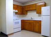 Thumbnail 5 of 6 - A kitchen with white appliances and wooden cabinets.