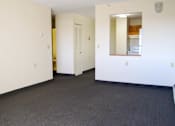 Thumbnail 1 of 6 - A large empty room with a door and a mirror on the wall.