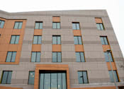 Thumbnail 9 of 10 - A building with a grey facade and orange accents.