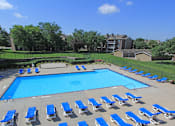 Thumbnail 1 of 25 - Huge swimming pool with spacious sundeck, poolside lounge chairs, beautiful landscaping, scenic views, lots of trees at LionsGate Apartments in Lincoln, Nebraska