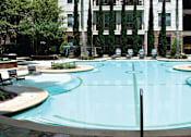 Thumbnail 31 of 37 - Luxury swimming pool with cabanas, poolside lounges, grilling stations, palm trees and beautiful landscaping at The Voss Apartments in Houston.
