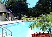Thumbnail 1 of 27 - Large swimming pool with poolside lounge chairs, beautiful landscaping, park-like setting, scenic views, and luxury resident clubhouse at Alpine Village Apartments in La Vista, Nebraska