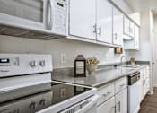 Thumbnail 38 of 42 - Bright white kitchen with wood plank floors, extra cabinet space and counter space at Woodlake on the Bayou Apartments